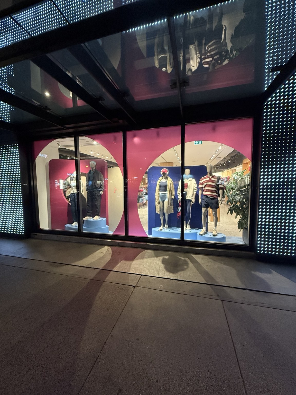 Retail storefront with large pink window graphics and illuminated exterior panels
